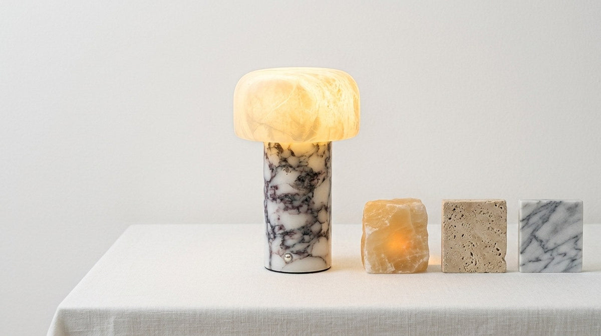 Alabaster, travertine and marble lamp pieces arranged together on a linen surface, one lit from within