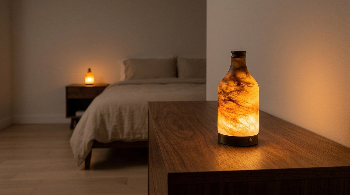 Bedroom at night lit low and warm by an alabaster cordless lamp, ceiling light off