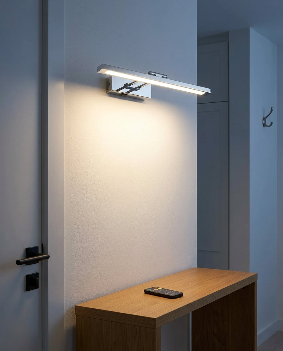 Rechargeable Swing-Arm Picture Light 16 in mounted on an off-white hallway wall above a low console, evening, warm pool of light on the wall