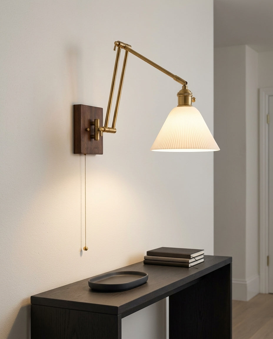 Ceramic Swing Arm Wall Sconce mounted on an off-white hallway wall above a low console, evening, warm pool of light on the wall