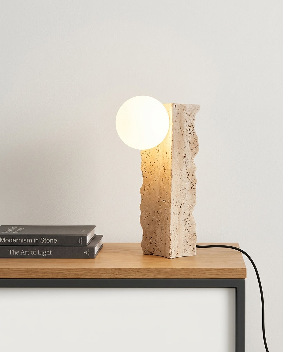 Travertine Column Table Lamp on an oak sideboard against an off-white wall, evening, a small stack of books beside it