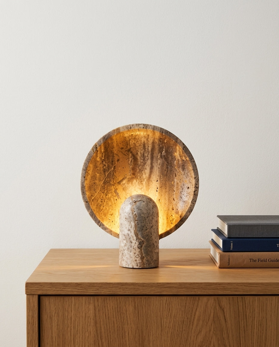 Travertine Table Lamp on an oak sideboard against an off-white wall, evening, a small stack of books beside it