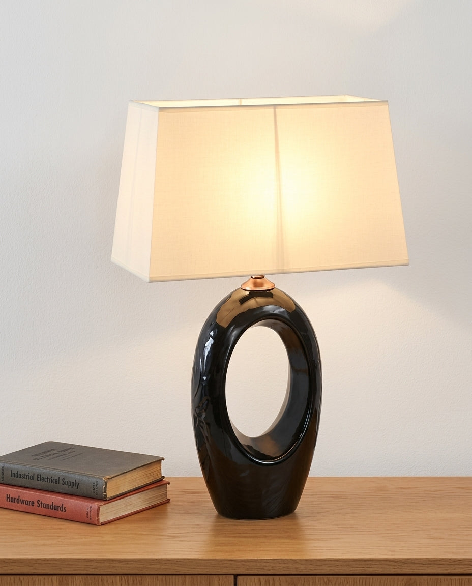 Ceramic and Fabric Table Lamp on an oak sideboard against an off-white wall, evening, a small stack of books beside it