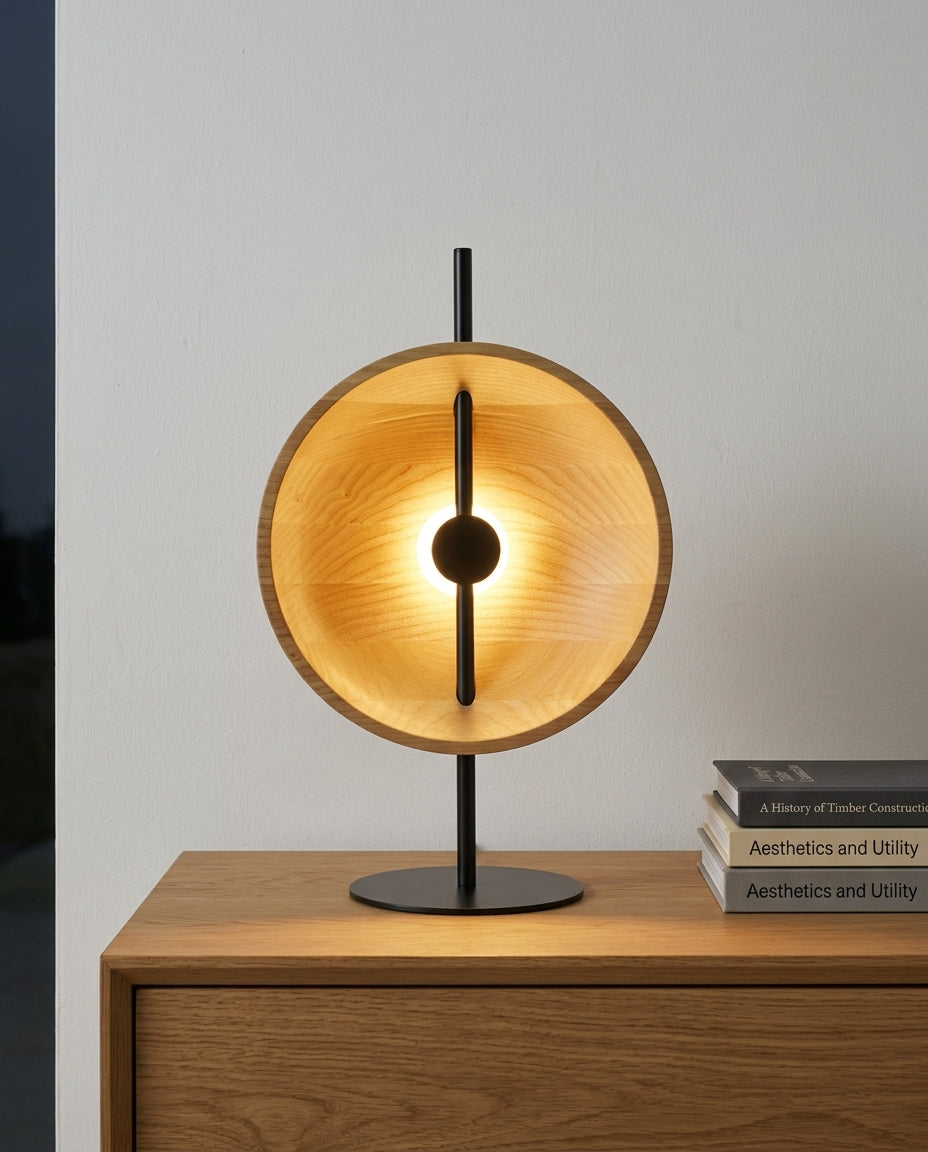Wood Disc Table Lamp on an oak sideboard against an off-white wall, evening, a small stack of books beside it