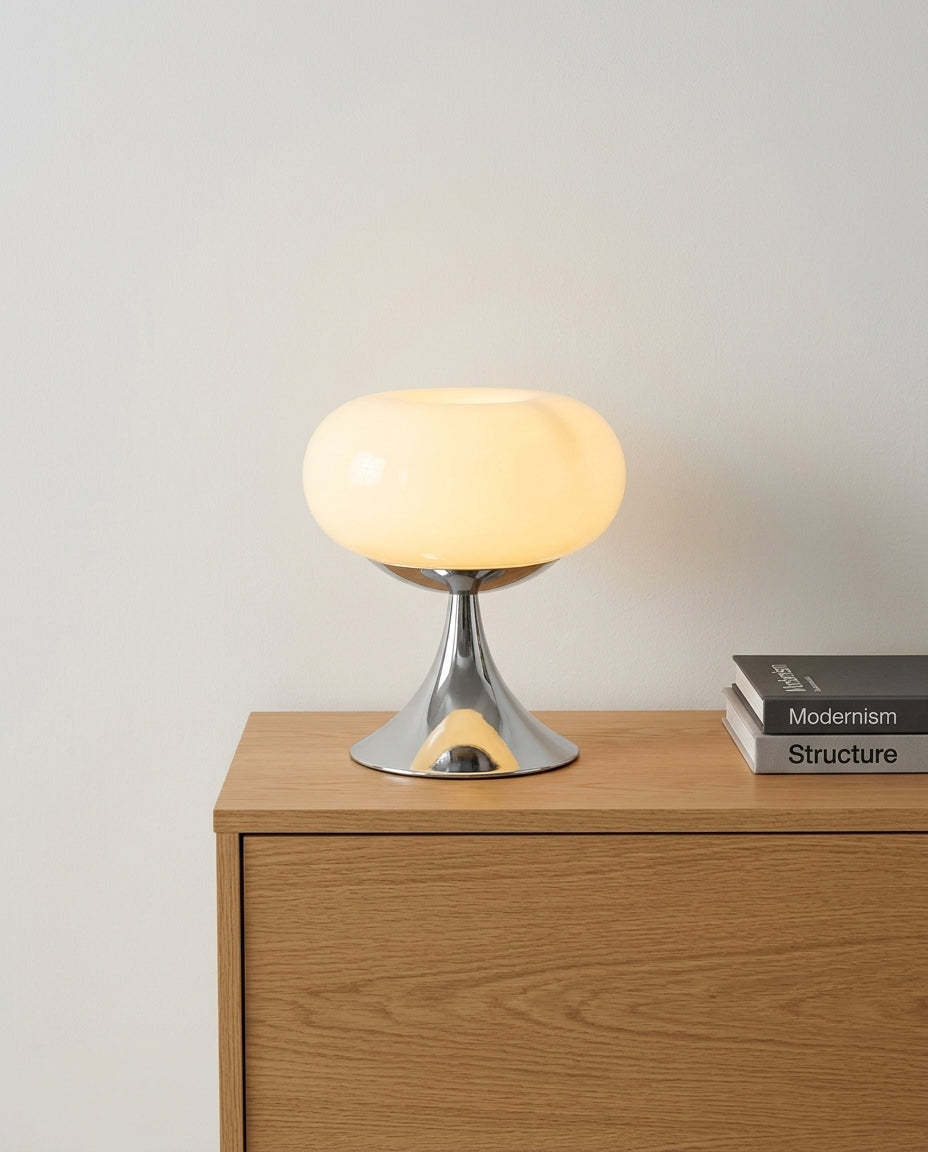 Rounded Glass Table Lamp on an oak sideboard against an off-white wall, evening, a small stack of books beside it