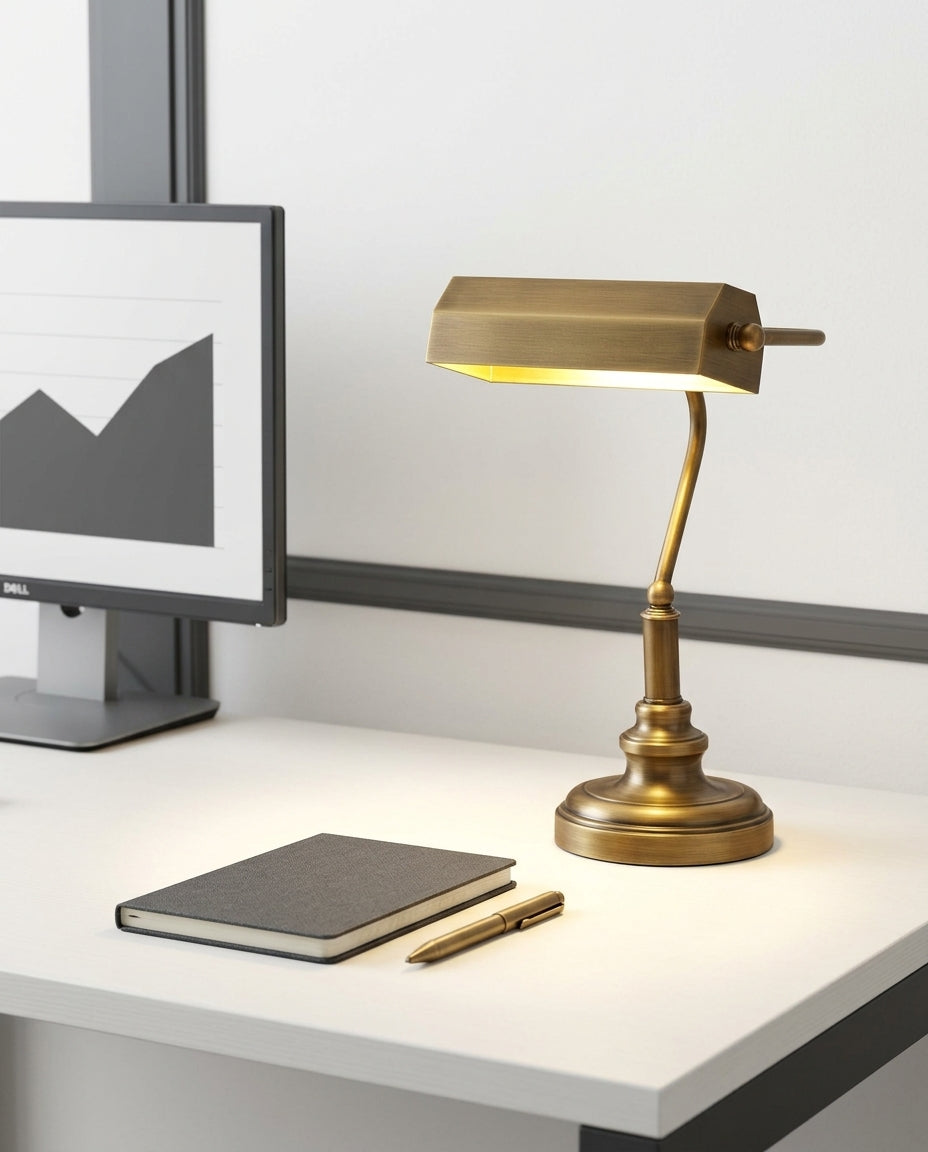 Antiqued Brass Library Desk Lamp on a tidy home-office desk with a monitor and a notebook, task light pooled on the desk surface