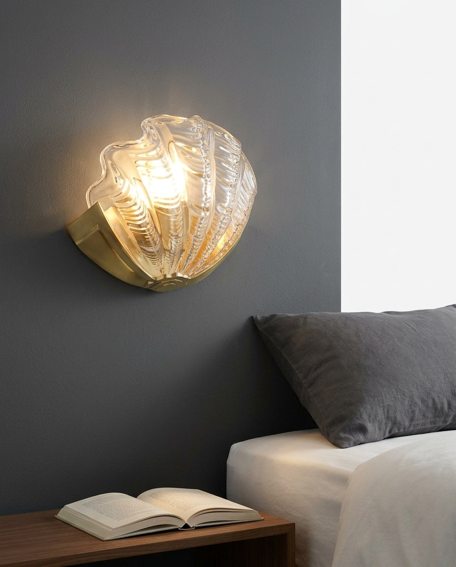 Seashell Glass and Brass Wall Sconce mounted on the wall beside a bed in place of a bedside lamp, reading light angled down