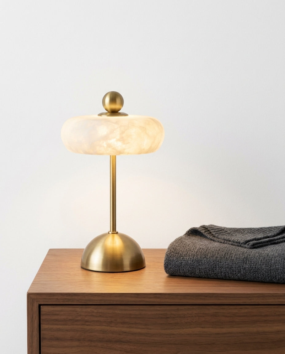Alabaster Disc Table Lamp on a bedside table beside a folded throw, warm evening light