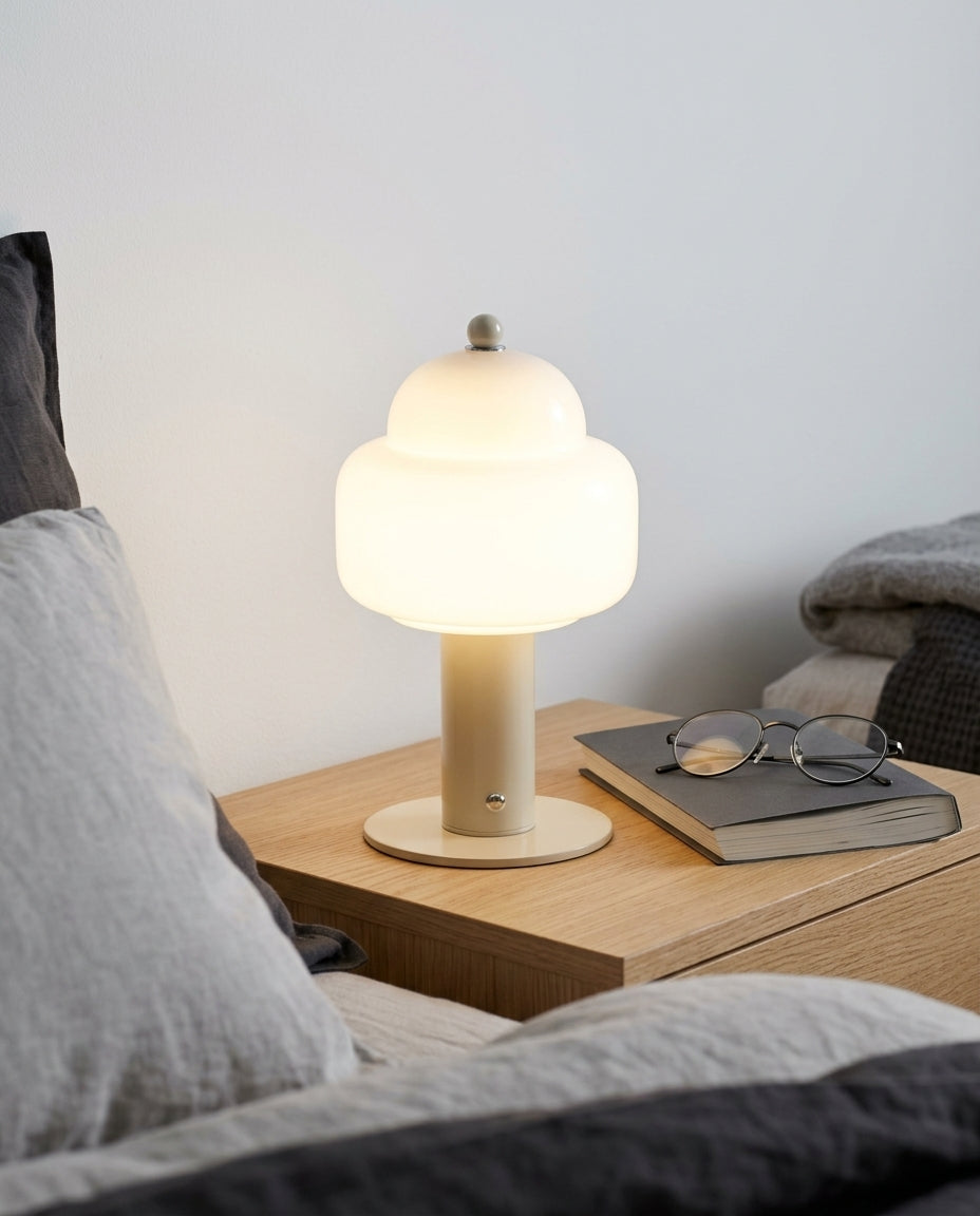 Rounded Glass Cordless Lamp on a bedside table beside a folded throw, warm evening light