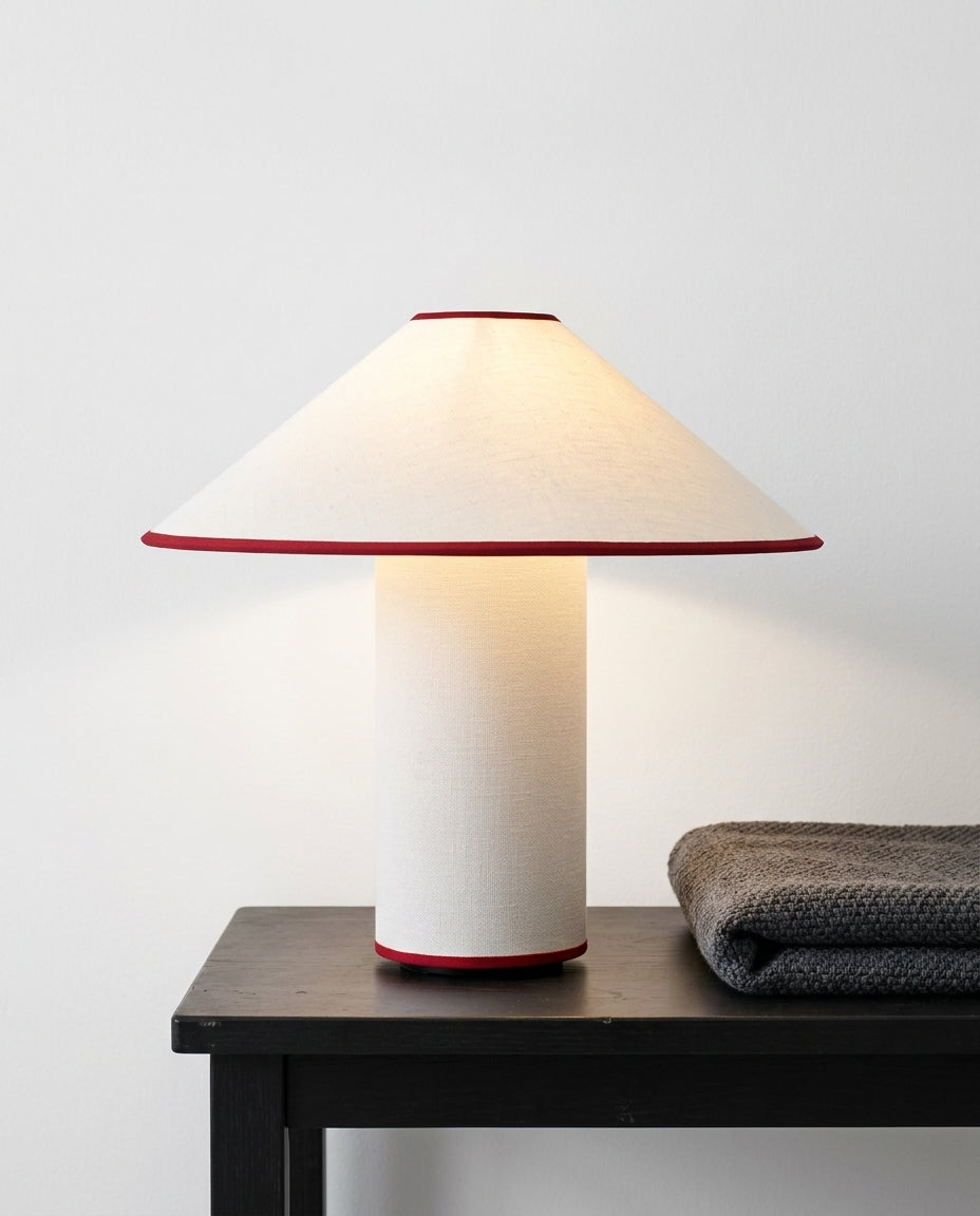 Fabric Drum Table Lamp on a bedside table beside a folded throw, warm evening light