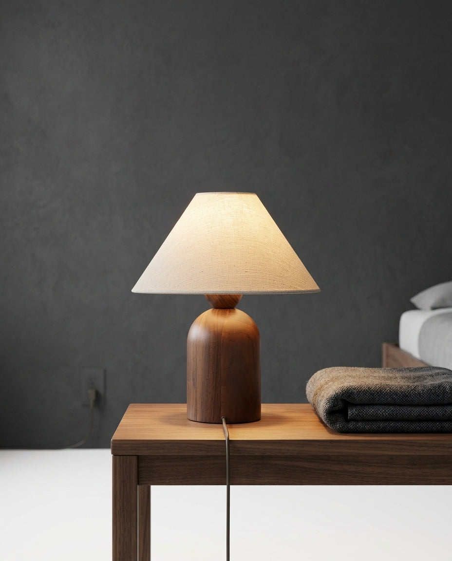 Linen and Walnut Table Lamp on a bedside table beside a folded throw, warm evening light