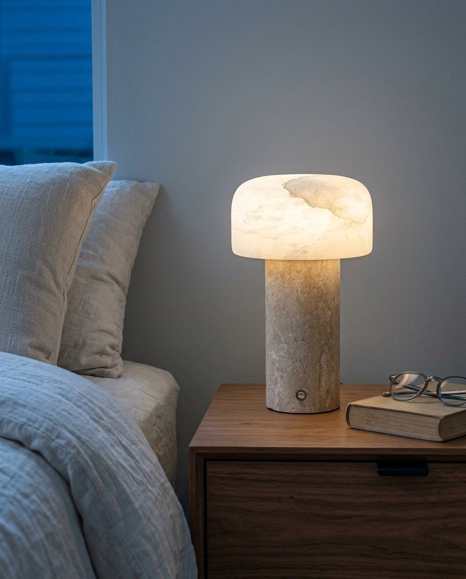 Travertine and Alabaster Cordless Lamp on a bedside table beside a folded throw, warm evening light