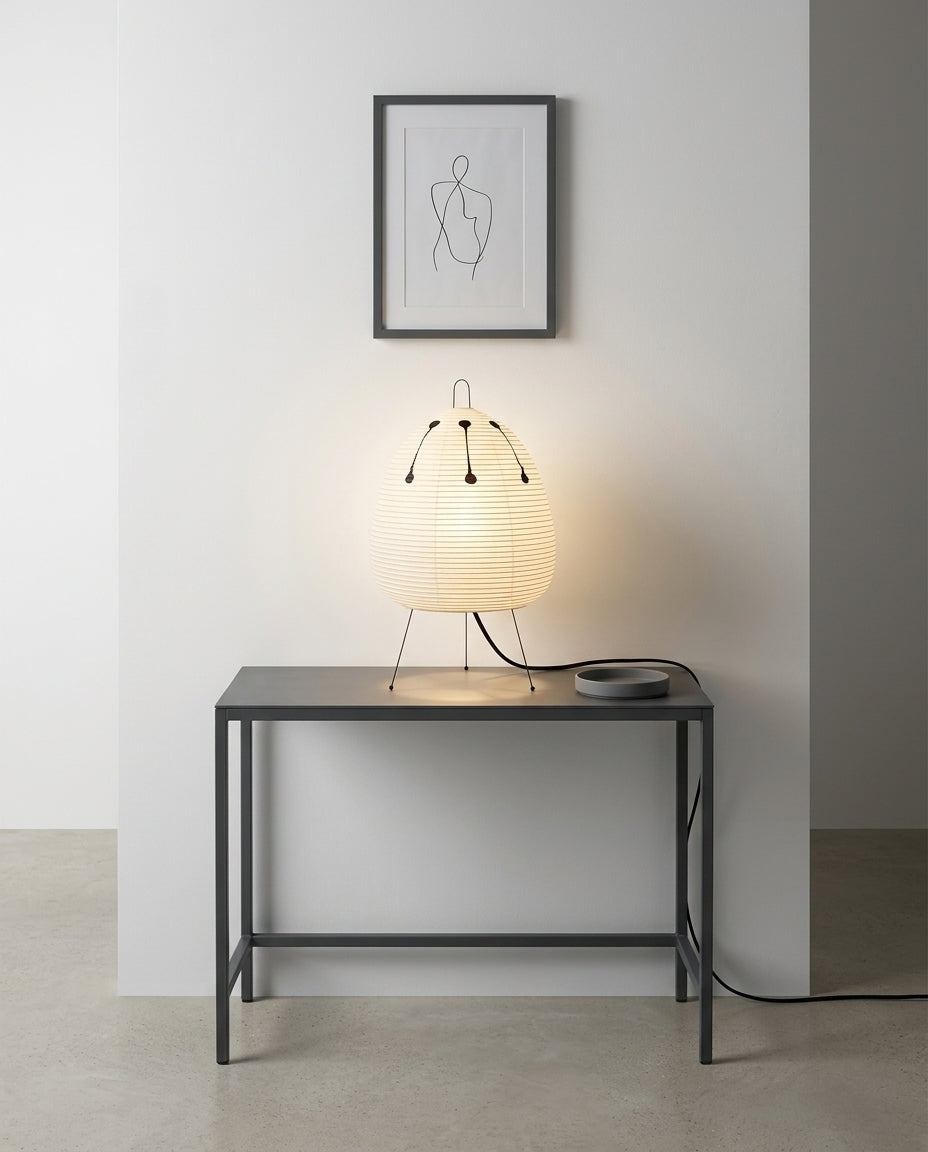 Rice Paper Tripod Table Lamp on an entryway console table below a framed print, evening
