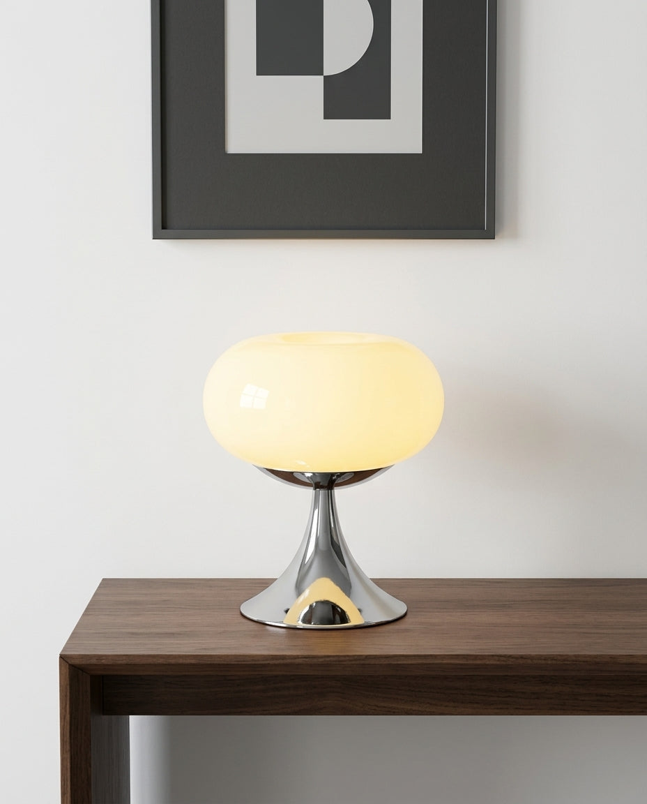 Rounded Glass Table Lamp on an entryway console table below a framed print, evening