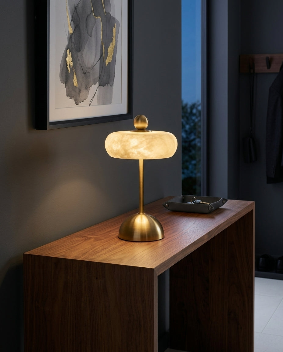 Alabaster Disc Table Lamp on an entryway console table below a framed print, evening
