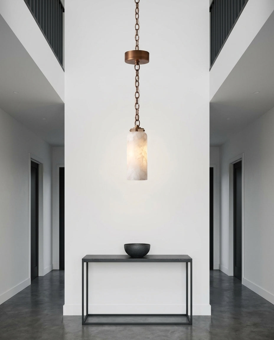Slim Alabaster and Brass Pendant Light hanging in a double-height entryway above a console table, evening