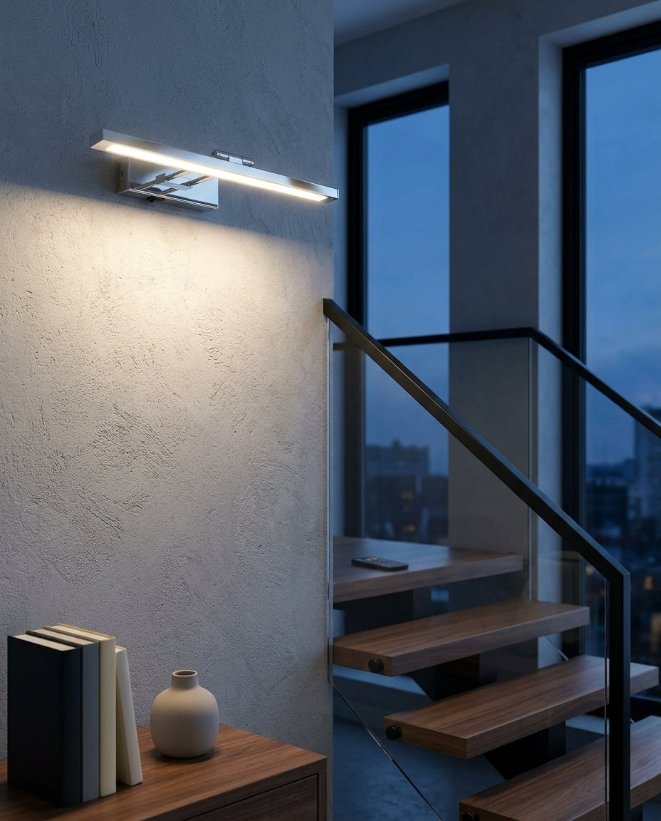 Rechargeable Swing-Arm Picture Light 16 in mounted on the wall of a modern staircase, the light grazing the wall texture