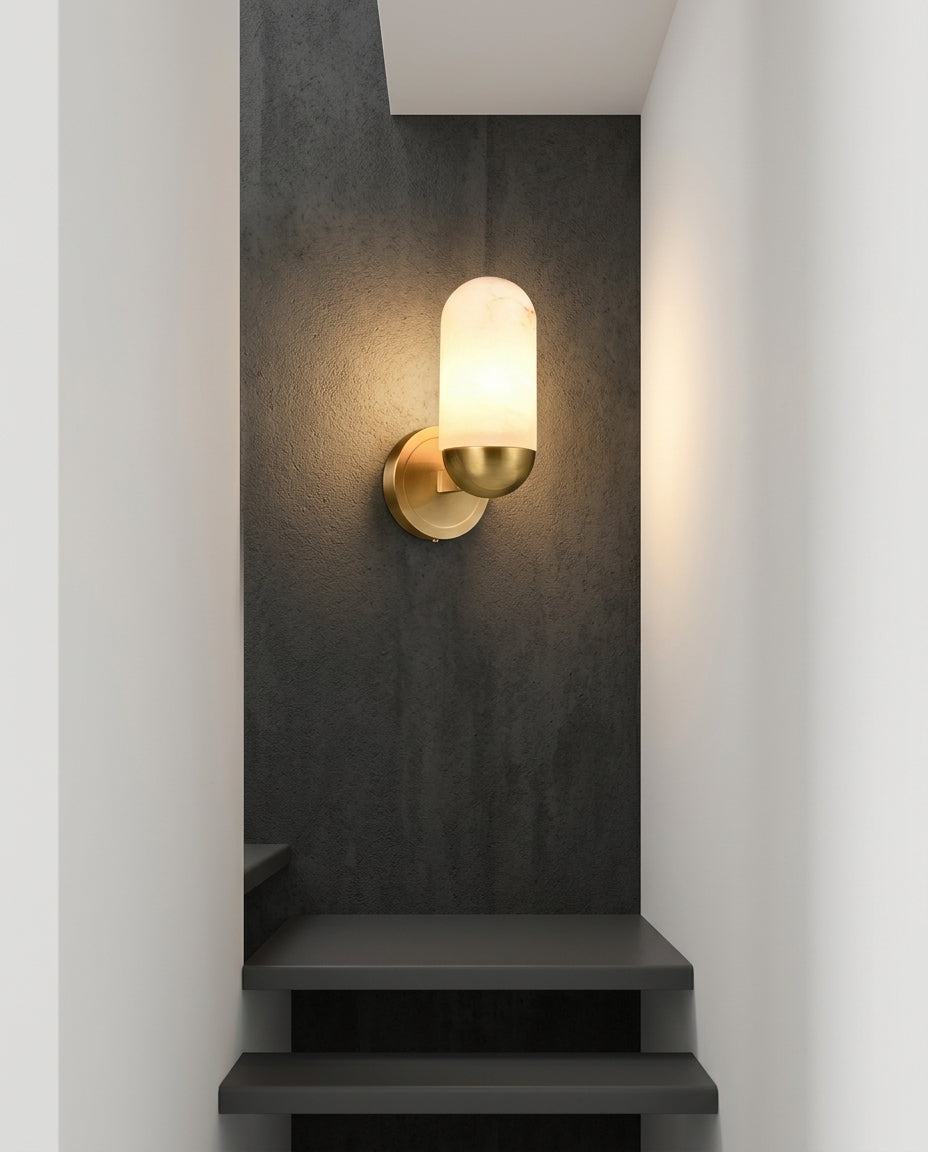 Alabaster Capsule Wall Light mounted on the wall of a modern staircase, the light grazing the wall texture