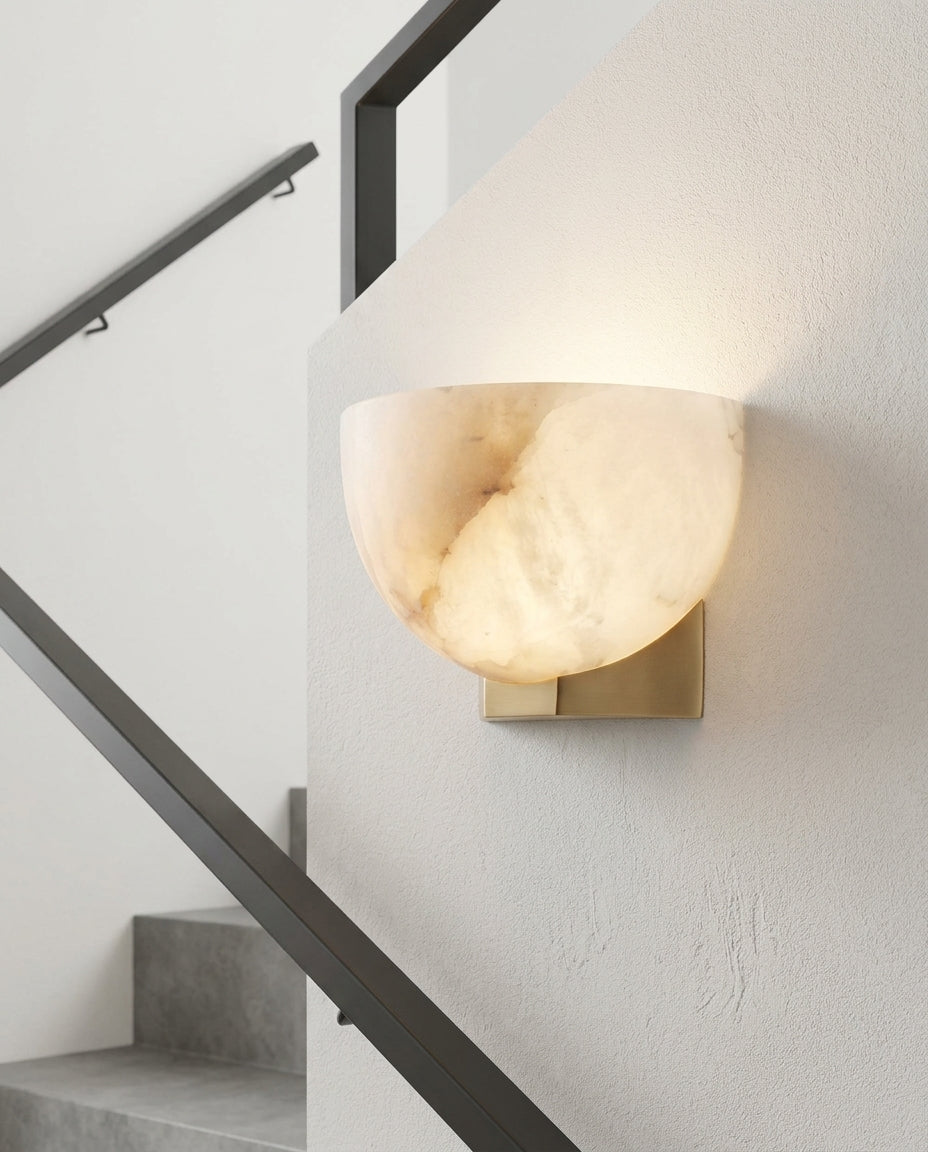 Brass and Alabaster Disc Sconce mounted on the wall of a modern staircase, the light grazing the wall texture