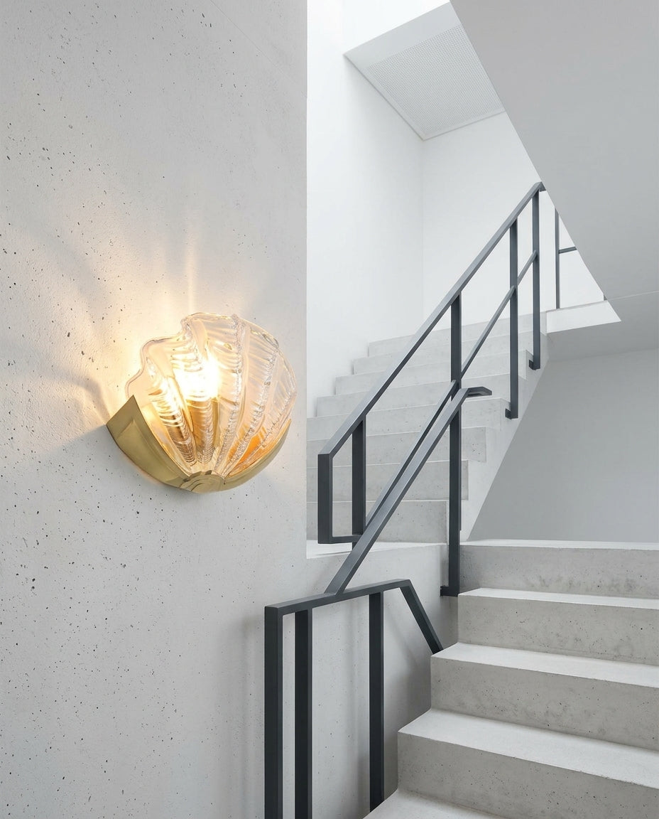 Seashell Glass and Brass Wall Sconce mounted on the wall of a modern staircase, the light grazing the wall texture