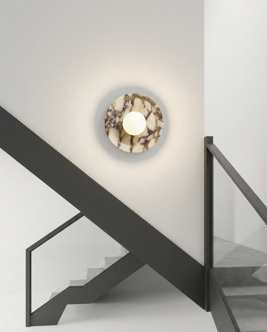 Purple Marble and Frosted Glass Wall Light mounted on the wall of a modern staircase, the light grazing the wall texture