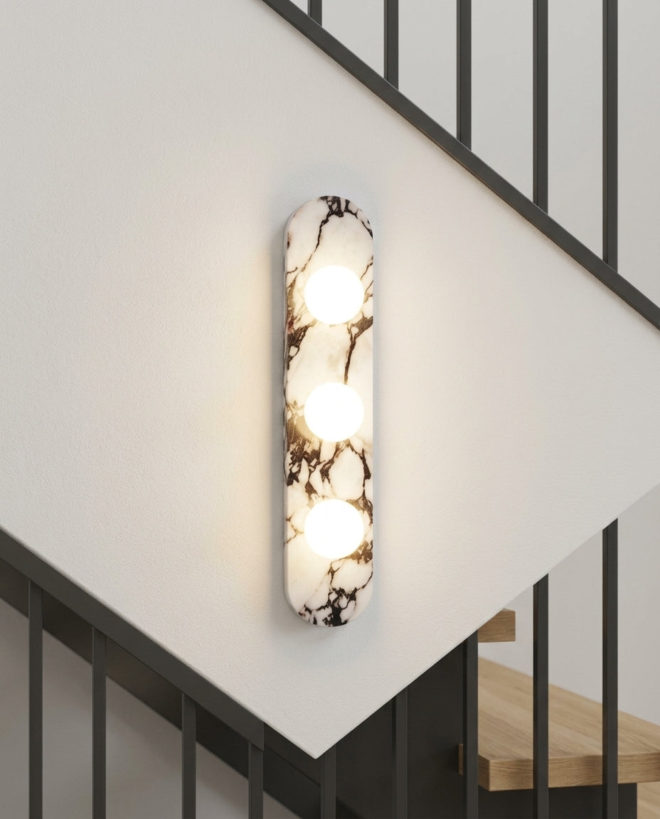 Marble and Opal Glass Wall Light mounted on the wall of a modern staircase, the light grazing the wall texture