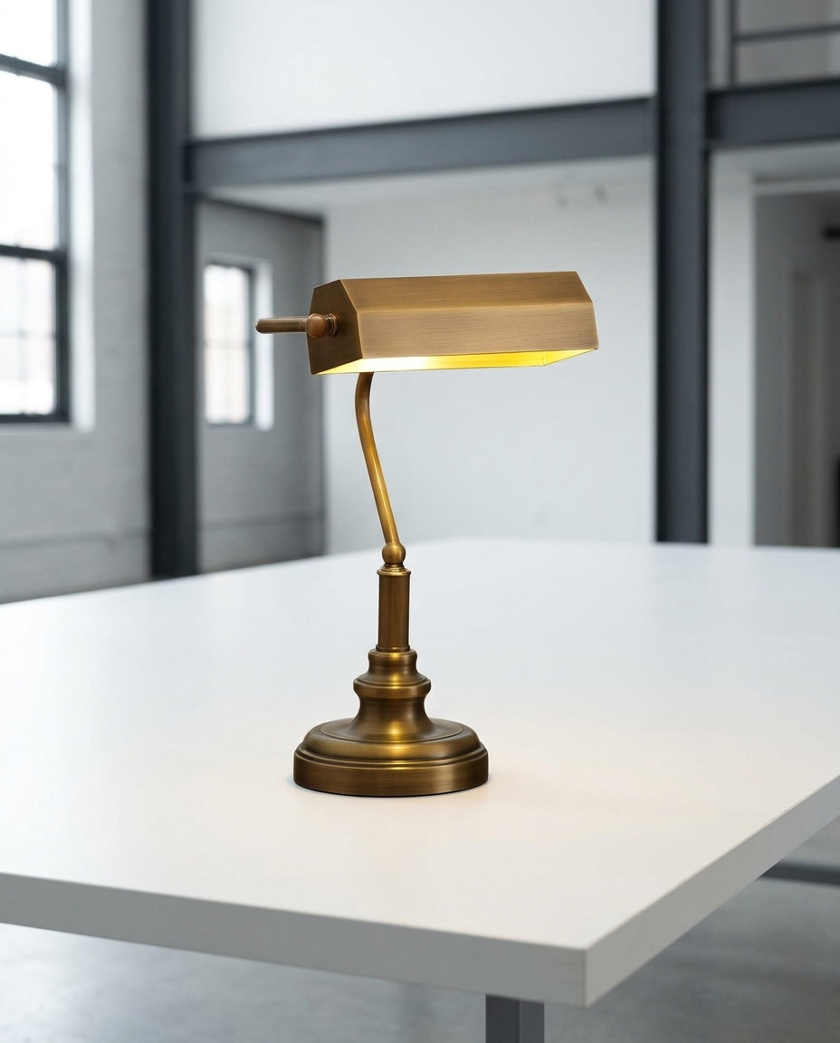 Antiqued Brass Library Desk Lamp on a wide work table in a bright modern studio, natural light from the left