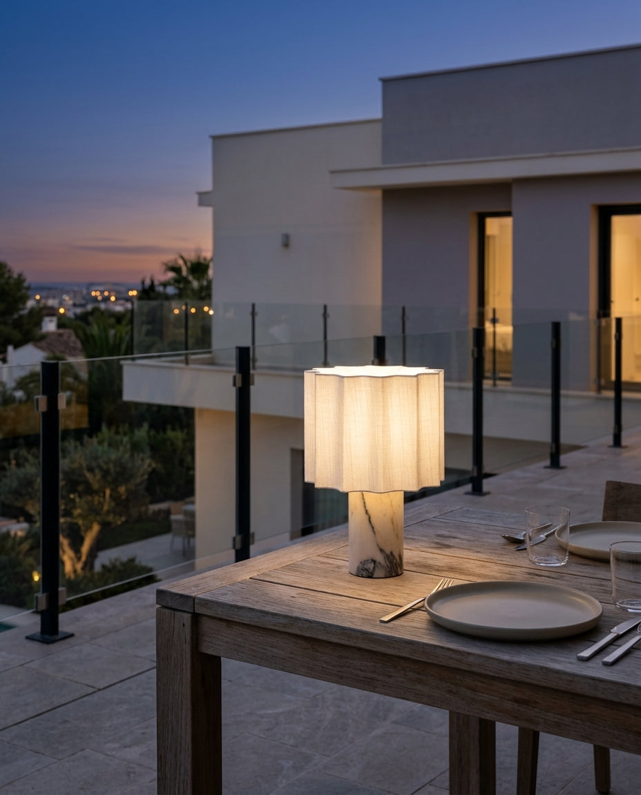 Marble and Fabric Cordless Table Lamp on an outdoor dining table on a modern terrace at dusk, no cable anywhere in frame