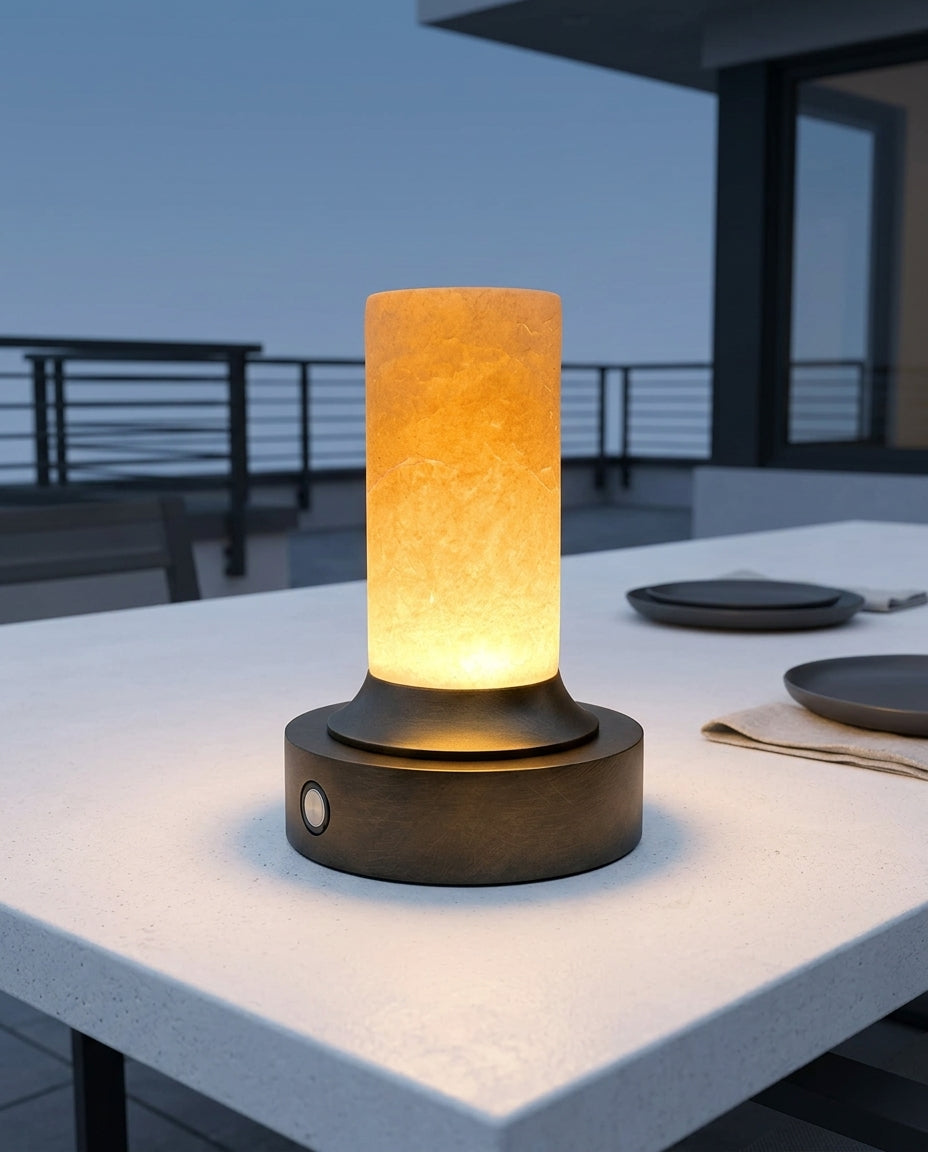 Bronze and Alabaster Cordless Lamp on an outdoor dining table on a modern terrace at dusk, no cable anywhere in frame