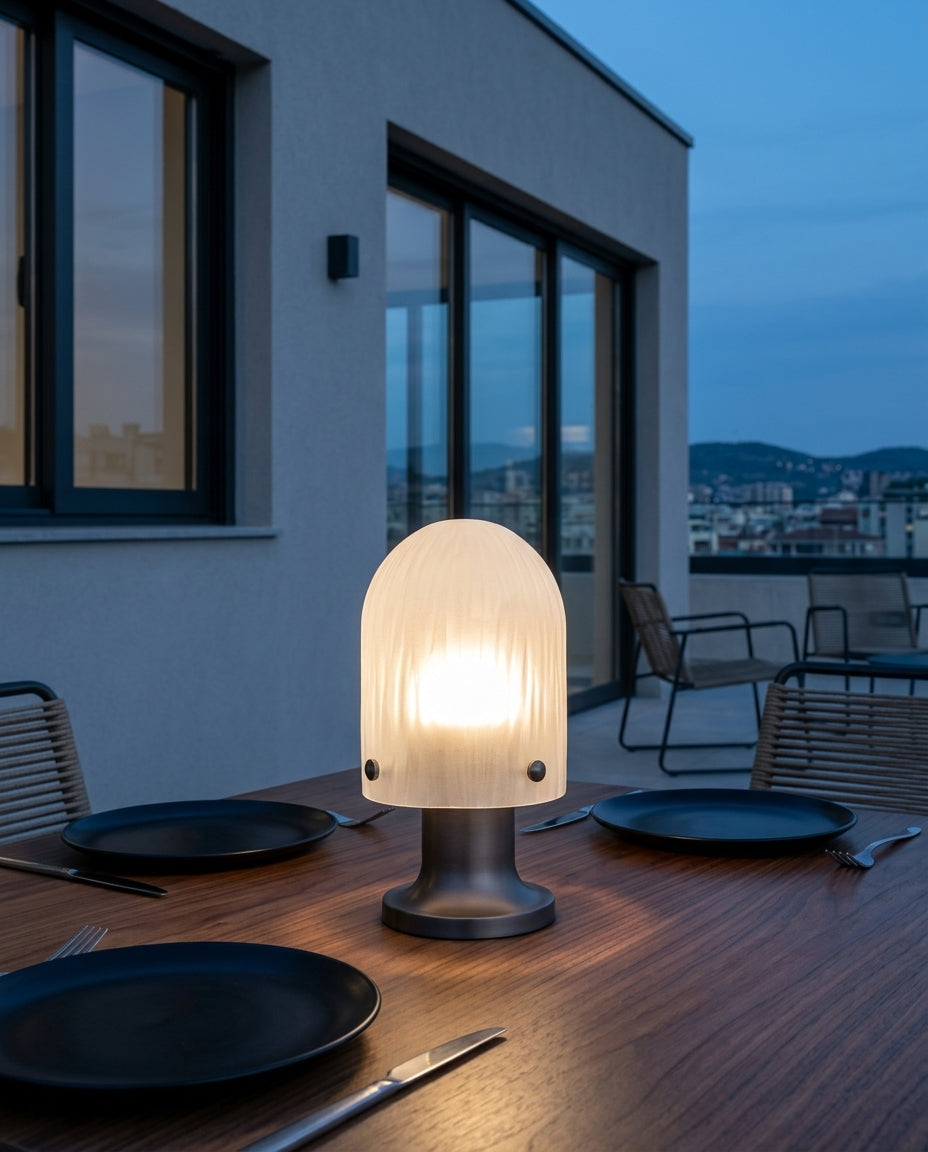 Ribbed Glass Cordless Lamp on an outdoor dining table on a modern terrace at dusk, no cable anywhere in frame